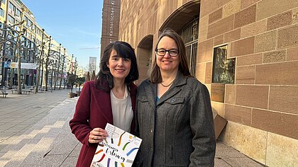 Simone Caliandro und Angela Schmid mit einem Plakat des Stuttgarter Osterwegs vor der Domkirche St. Eberhard