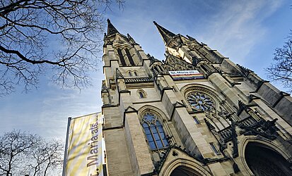 Kirche mit Doppelturmfassade, Fahne mit "St. Maria als ..."