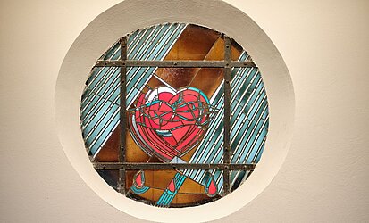 rundes Kirchenfenster in der Kirche St. Fidelis im Stuttgarter Westen mit einem roten Herz in der Mitte 
