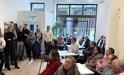 Menschen stehen und sitzen bei der Einweihung in den frisch renovierten Räumen der Pauline 