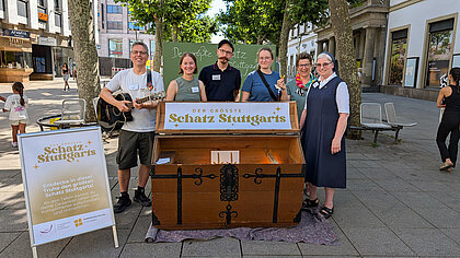 Team-Foto vor einer großen Holztruhe mit der Aufschrift "Der größte Schatz Stuttgarts"