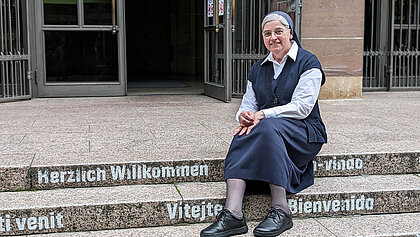 Schwester Nicola Maria sitzt auf der Treppe vor der Domkirche St. Eberhard
