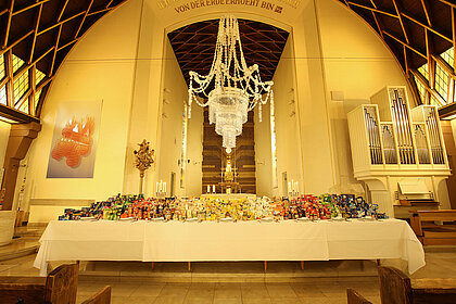 In der katholischen Kirche Christus König werden die Erntedankspenden in diesem Jahr auf einer großen, schön eingedeckten Tafel unter einem Kronleuchter aus weggeworfenen Einwegbechern präsentiert. 