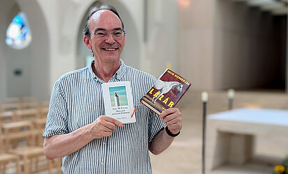 Pfarrer Stefan Karbach hält zwei Bücher in seinen Händen