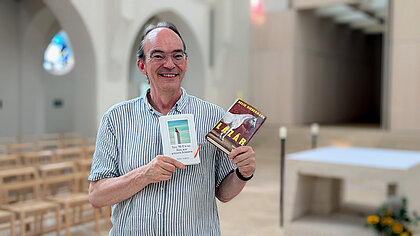 Pfarrer Stefan Karbach hält zwei Bücher in seinen Händen