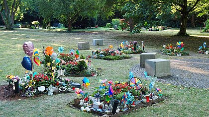 Zu sehen ist die Grabstätte für die Kleinsten der Kleinen auf dem Pragfriedhof. Die Gemeinschaftsgräber sind mit vielen bunten Windrädern geschmückt.